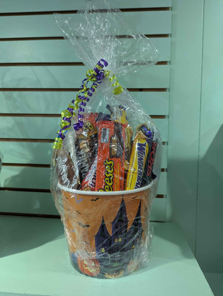 Halloween-themed candy bucket with wrapped candies on a light background