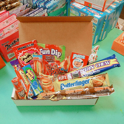 Photo of a box with a variety of chocolate bars and candies displayed open and overflowing. Charleston Chew, Butterfinger, Fun Dip, Pop Rocks, Hubba Bubba, Cow Tales and much more!